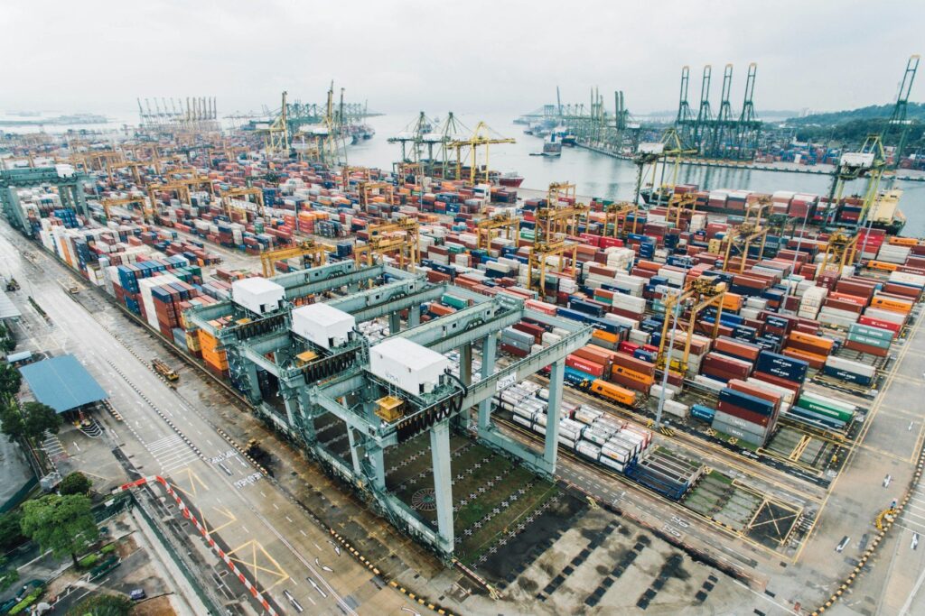 Aerial view of a busy container port with stacked shipping containers and gantry cranes