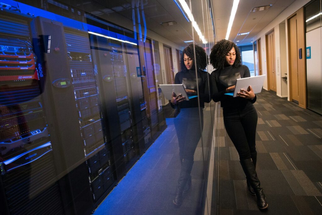 Two engineers with laptops working between server racks in a data centre